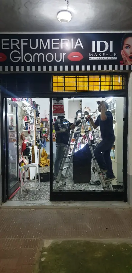 Técnicos reparando la cortina de una perfumería de noche en Rosario